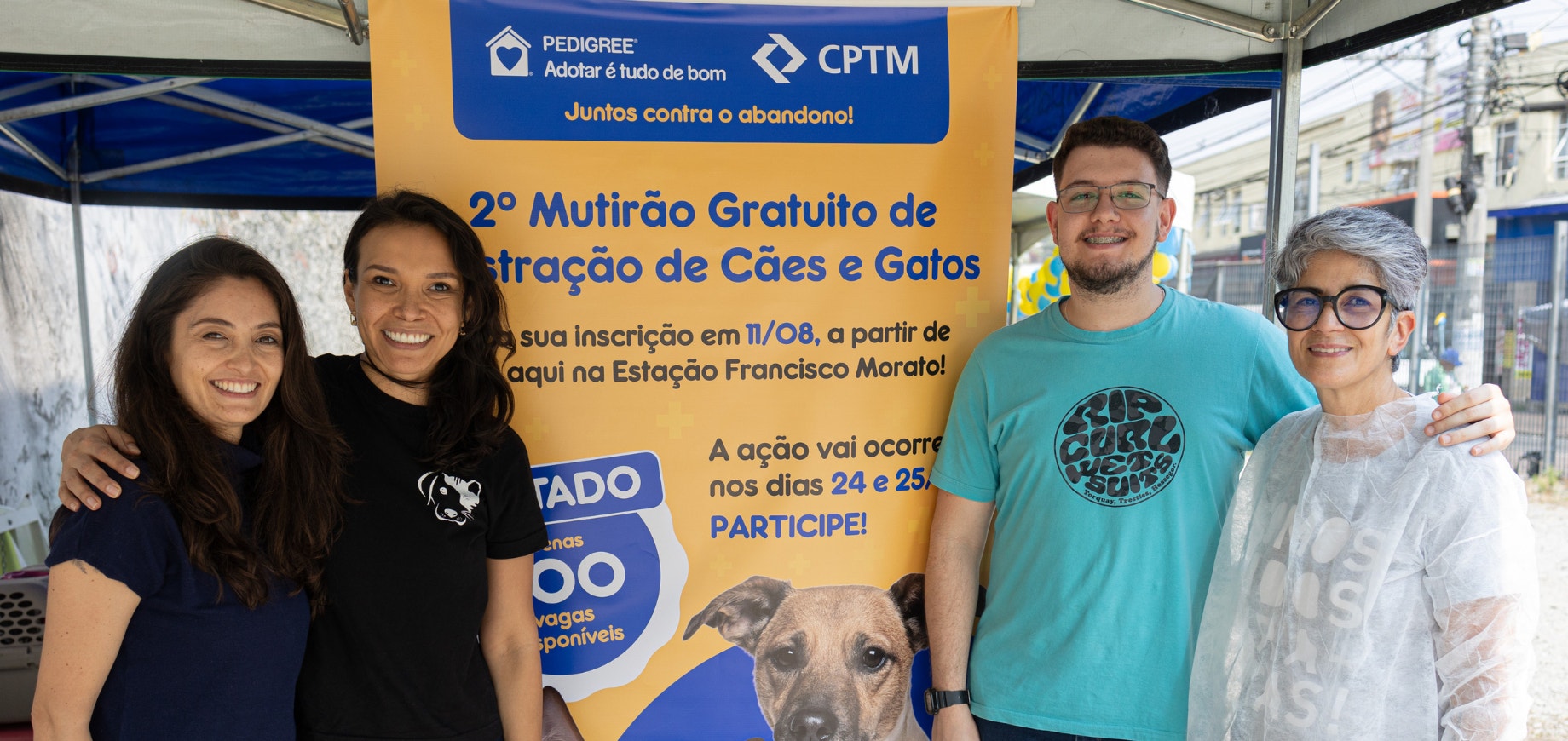 4 pessoas ao lado de um cartaz com informações sobre o 2º mutirão gratuito de castração de cães e gatos